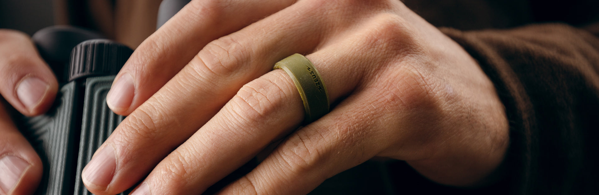 man holding binoculars with zeus olive drab groove ring