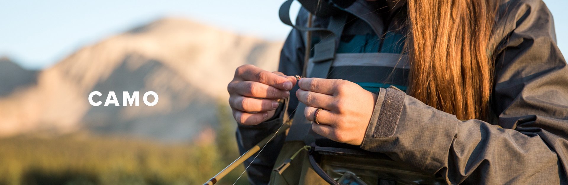 Camo, a woman ties a fly while fishing