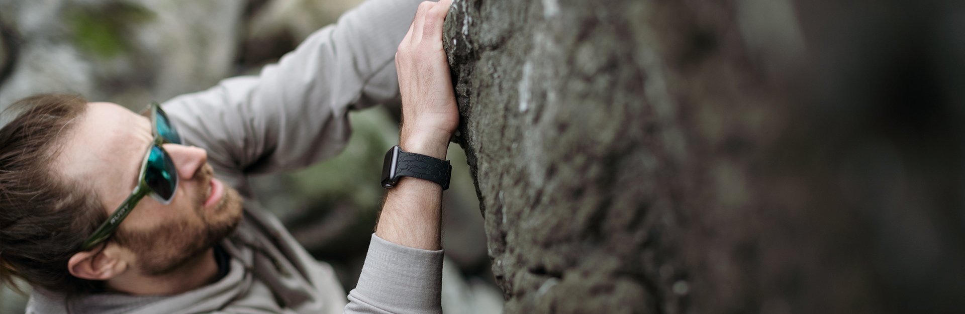 Men's Watch bands, a man wearing sunglasses and a black watch band climbs a rock face