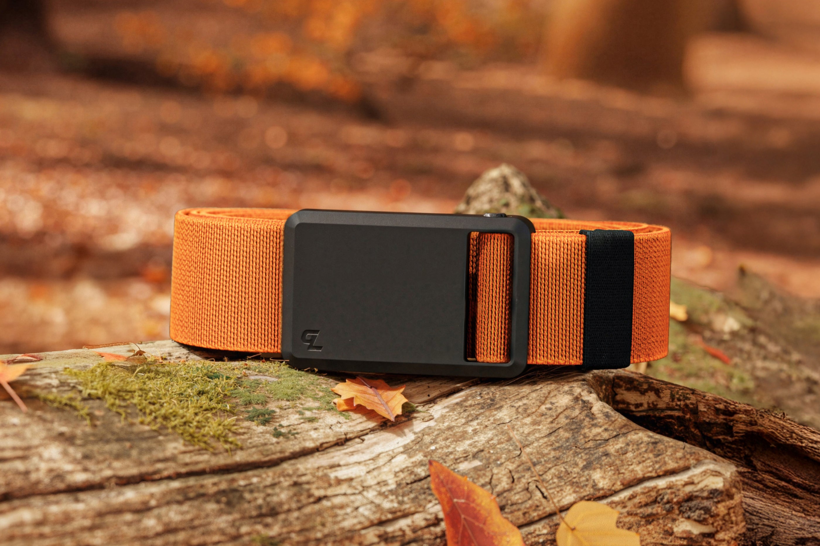 Orange and black belt on a wooden surface with a blurred natural background