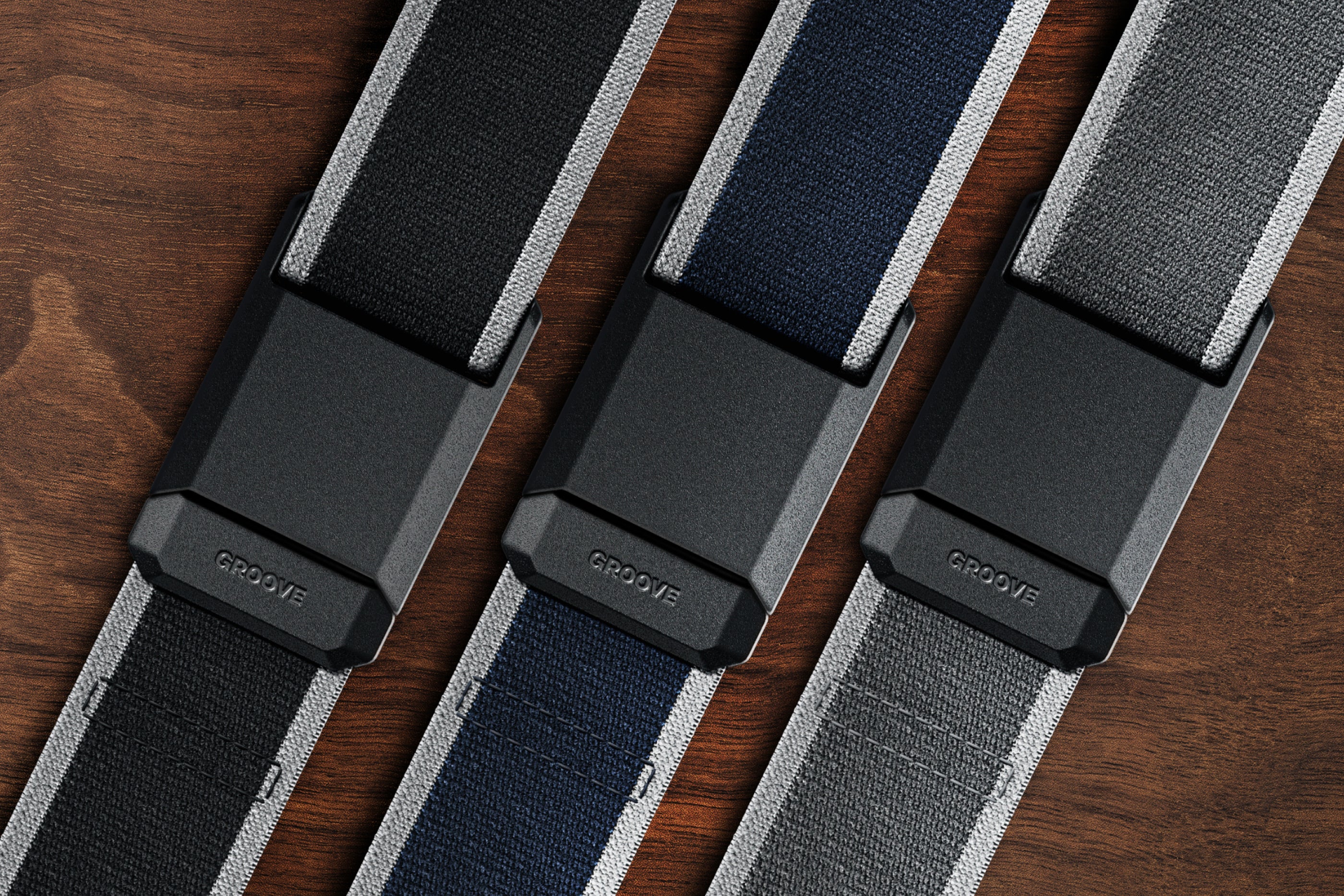 Three belts in black, blue, and gray on a wooden surface