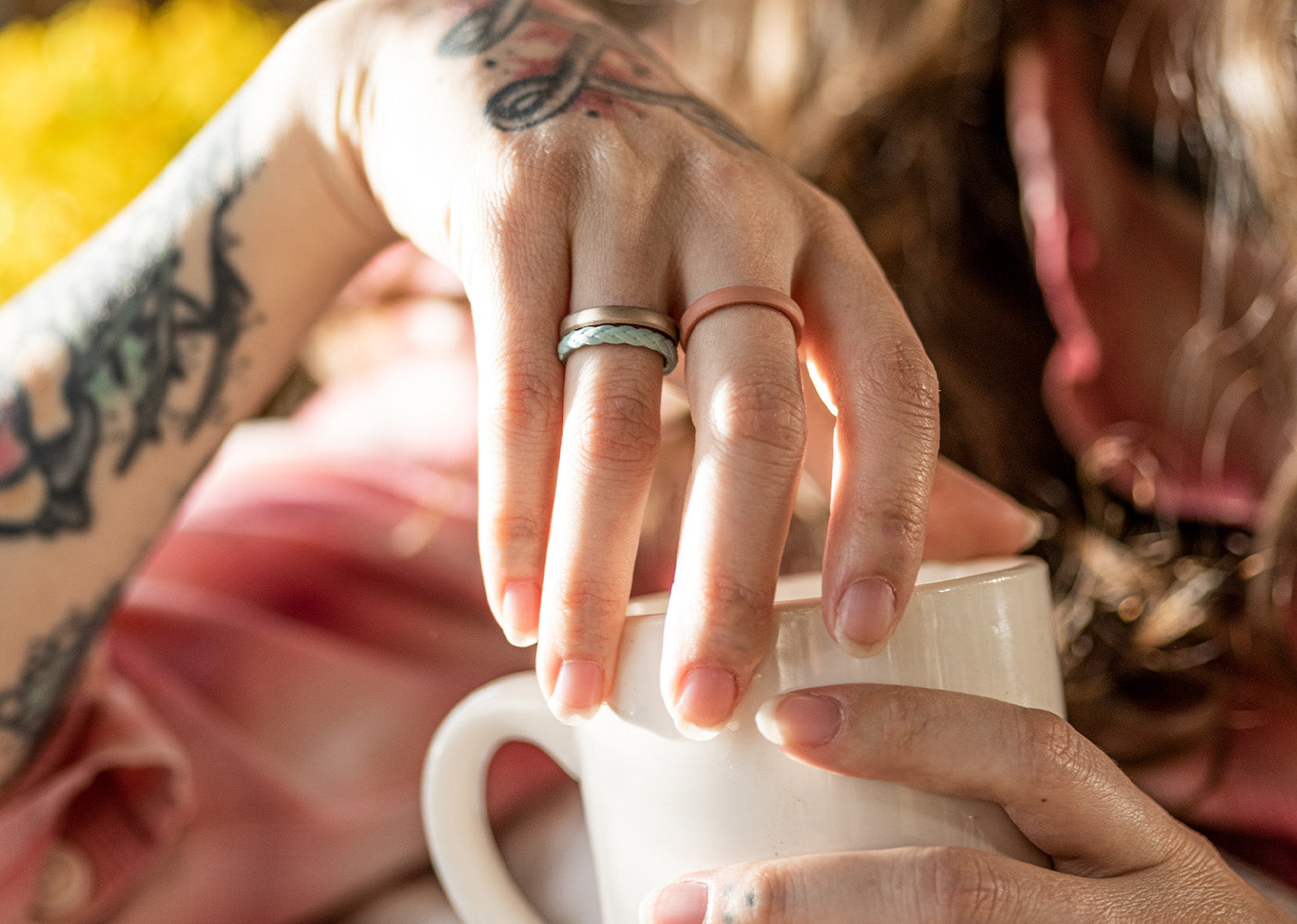 image of a woman's hand holding a coffee cup wearing Groove Life stackable rings