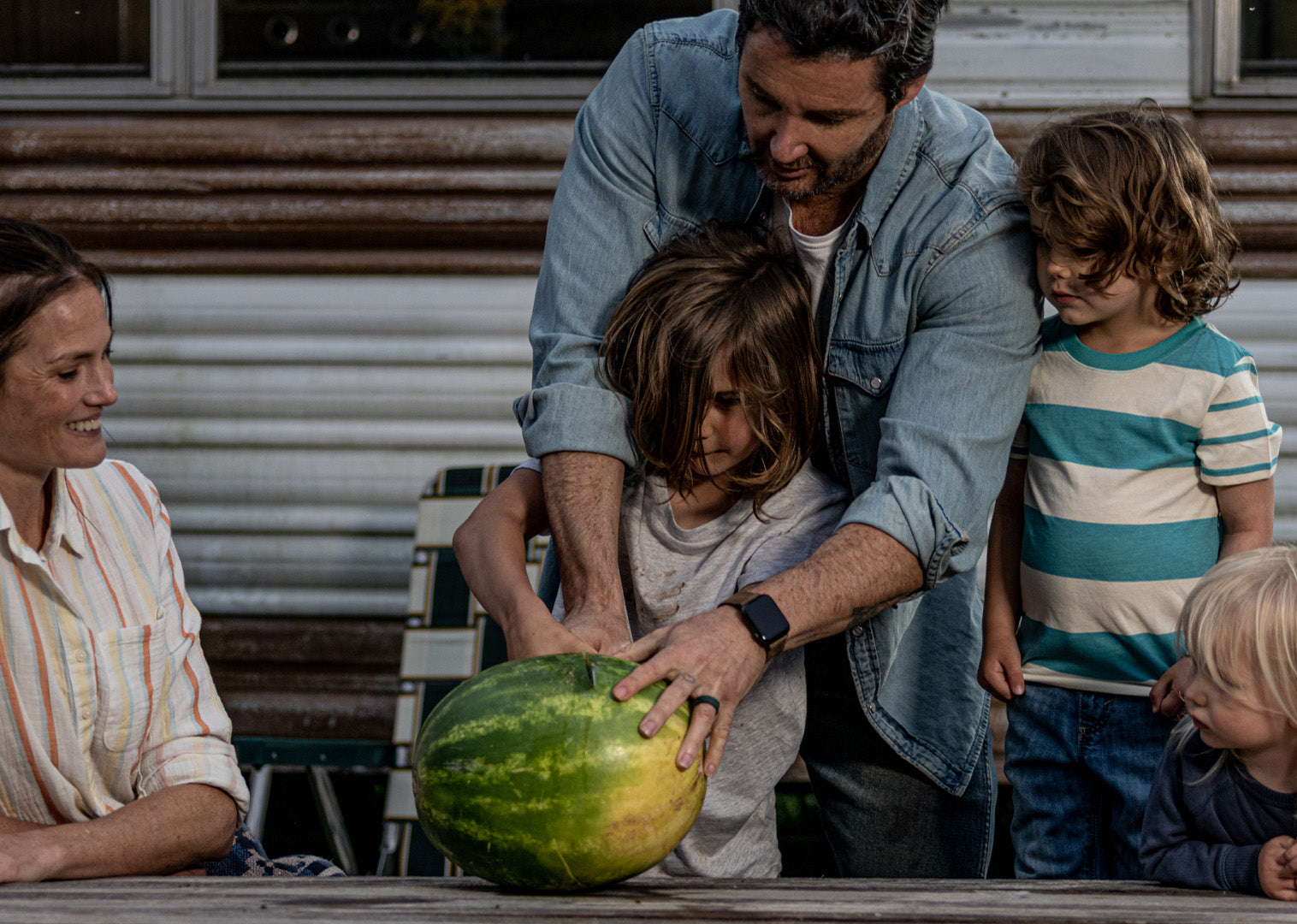 Image of a family cutting a watermelon outside wearing a Groove life watch band and rings