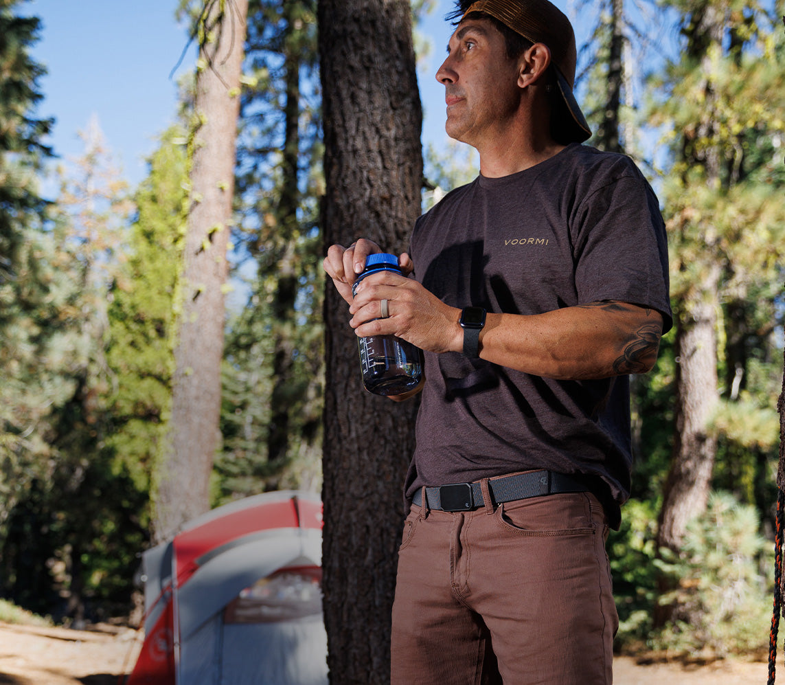 new mens products, pictured is a man holding a water bottle in the woods, wearing a deep stone groove belt and flat earth zeus ring.