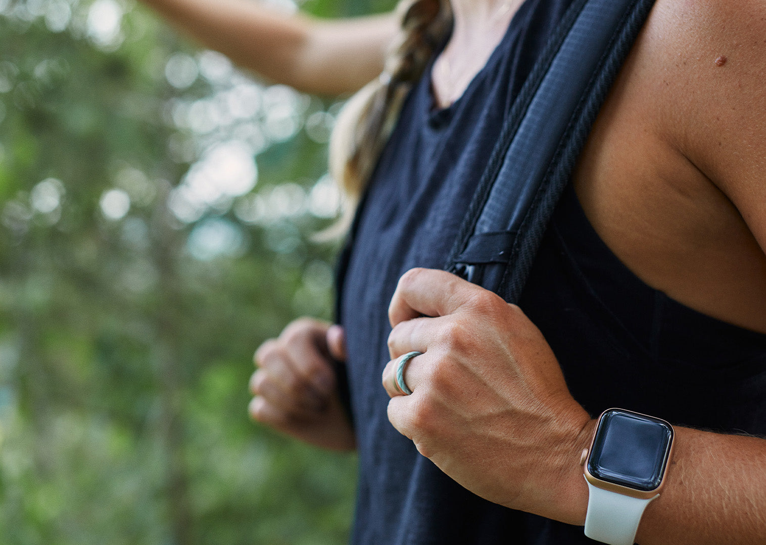 woman wearing a backpack holding the straps and featuring a Groove Life Apple watch band