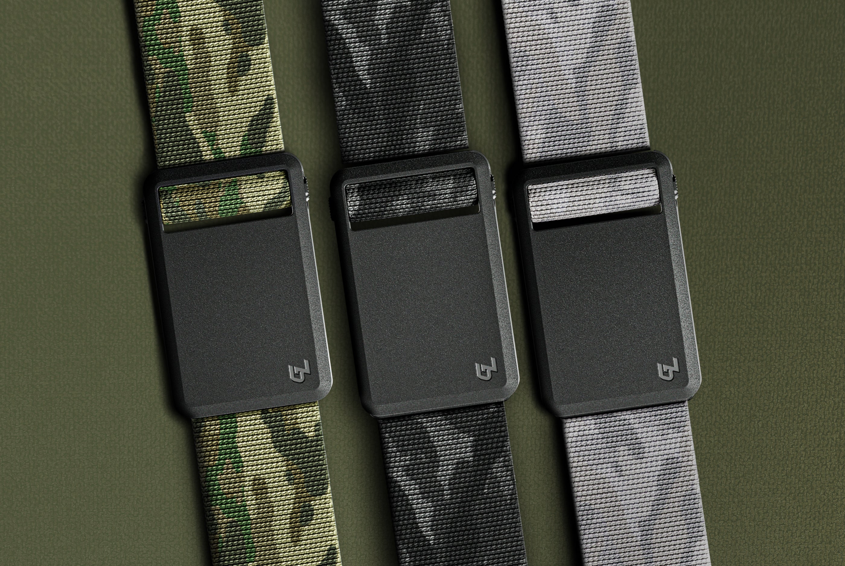 Three belts with camouflage patterns and black buckles on a green background