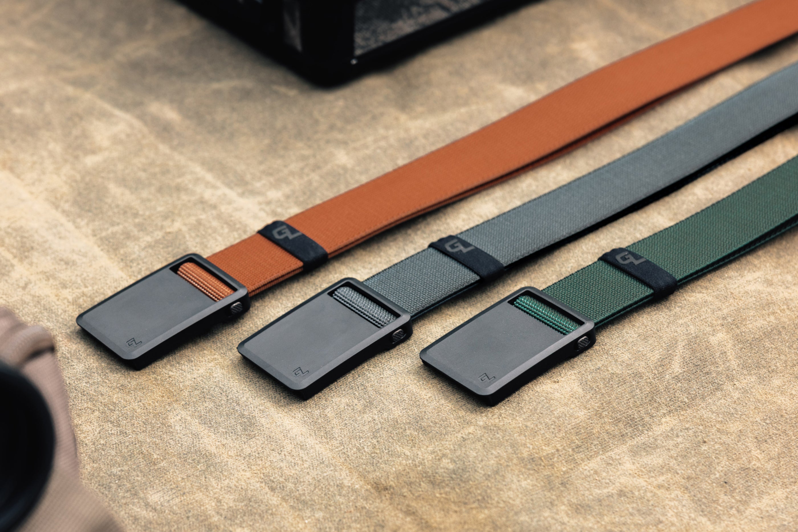 Three belts with different color options on a textured surface