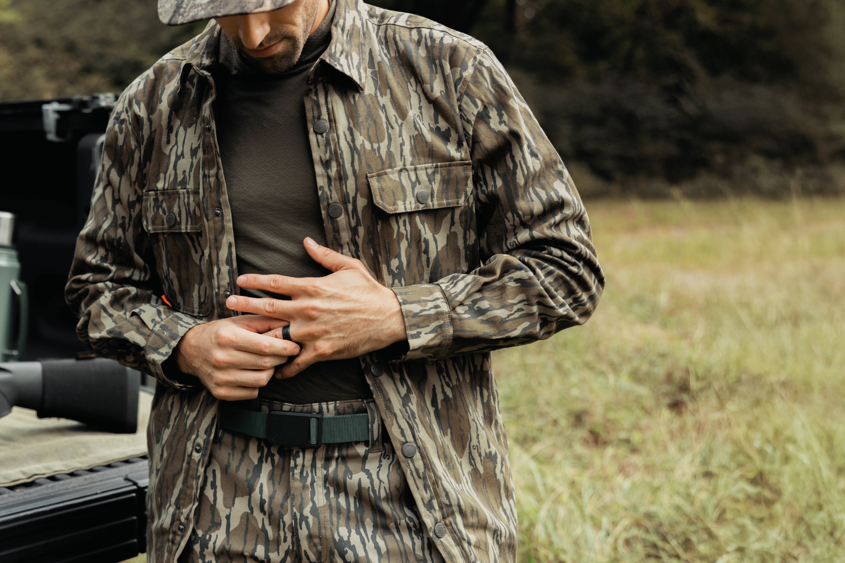 Man in camouflage clothing standing outdoors with a blurred background