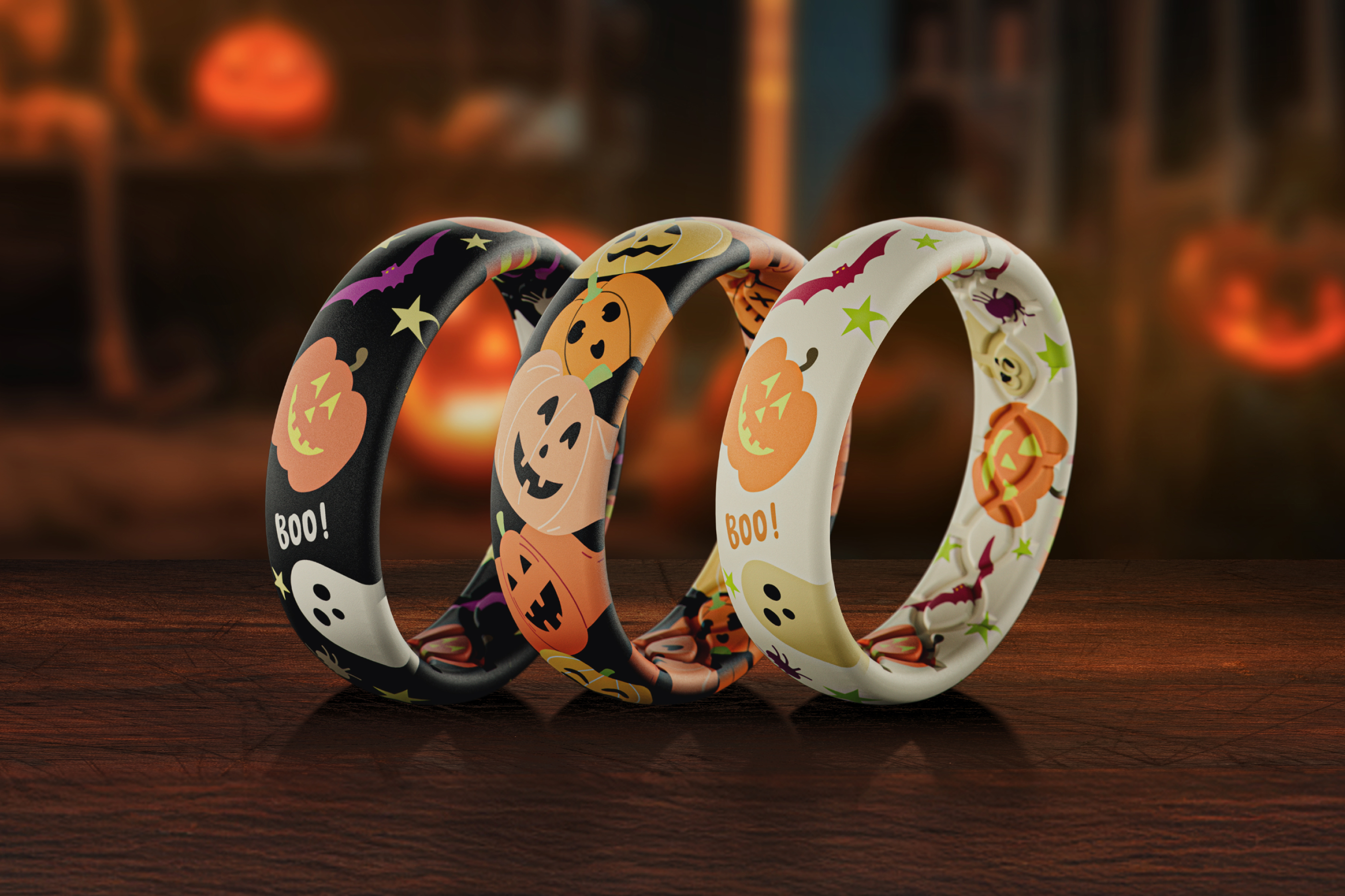 Three Halloween-themed bracelets on a wooden surface with pumpkins in the background.