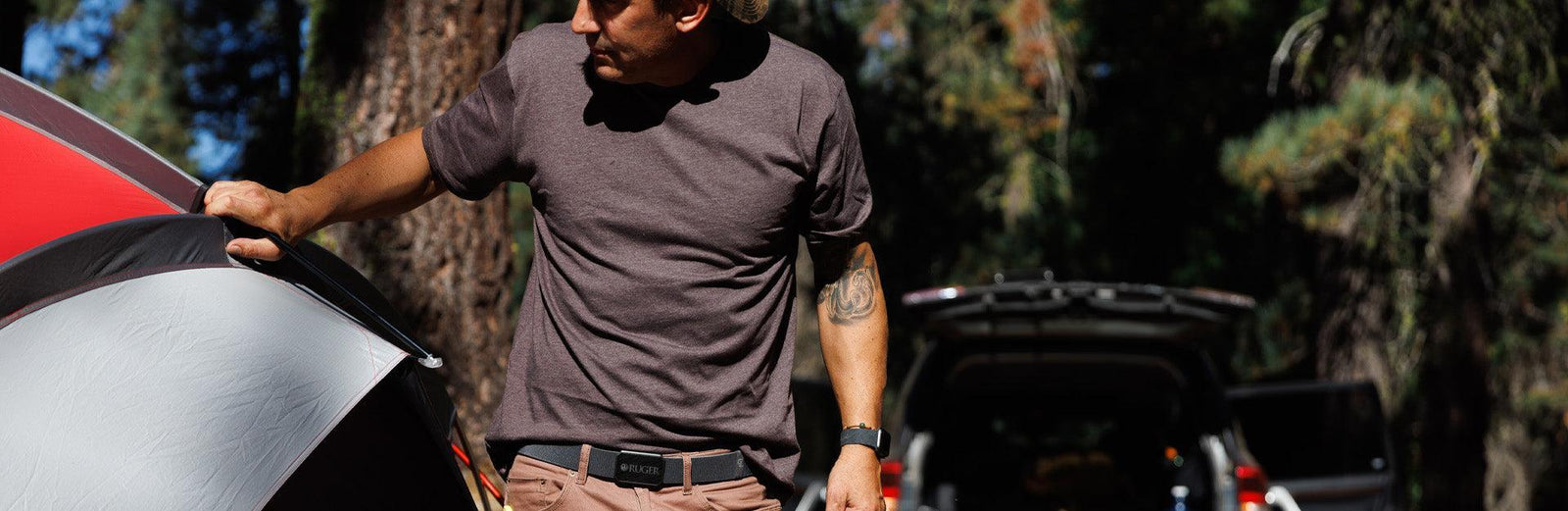 man outside holding on to a camping tent wearing a Groove Life belt