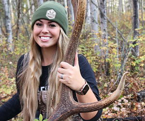 Katie Van Slyke crouches next to the antlers of an elk she's hunted