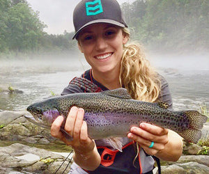 Nicole Oliver poses with a pretty trout in front of a foggy river