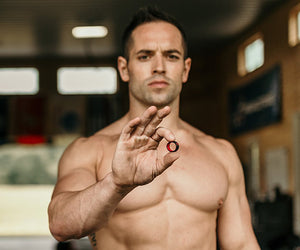 Rich Froning holds up a groove ring while shirtless
