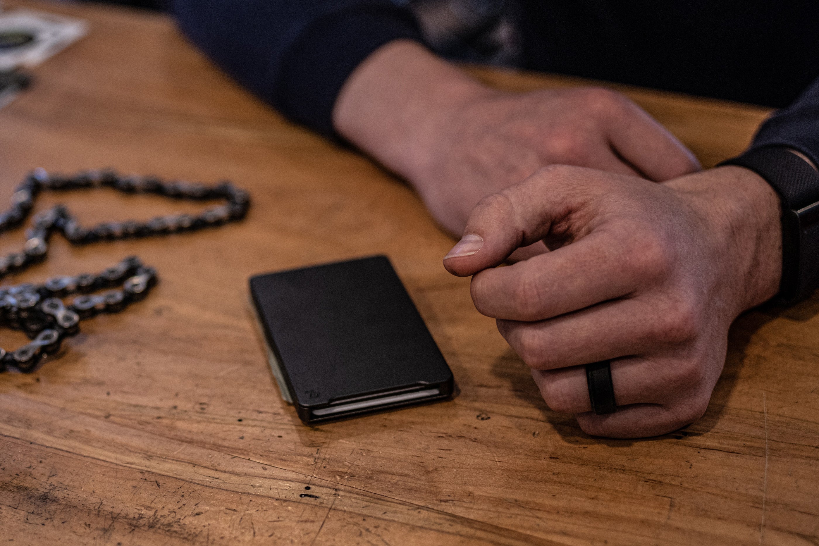 man's hands leaning on a table next to a Groove Life wallet