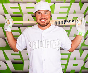 Hunter Renfroe poses in front of a banner with his Padres-styled bat over his shoulders