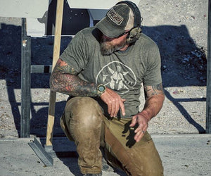 Jim Erwin on one knee at a firearms range, wearing hearing protection
